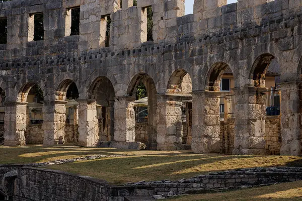Hırvatistan 'ın Pula kentindeki antik miras. Antik Roma arenasının kemerleri. Tarihi amfi tiyatronun ayrıntıları, mavi arka plandaki yüksek duvarların geniş açılı görüntüsü..