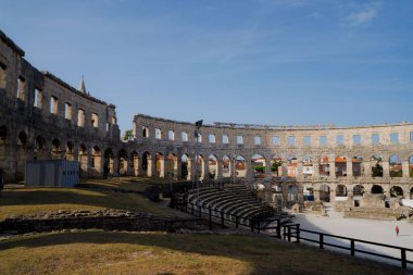 Pula, Hırvatistan - 22 Ağustos 2024: Hırvatistan 'ın Pula kentinde antik miras. Antik Roma arenasının kemerleri. Tarihi amfi tiyatronun ayrıntıları, mavi arka plandaki yüksek duvarların geniş açılı görüntüsü..