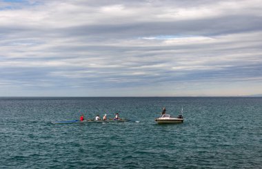 Trieste - İtalya - 30 Mart 2025: Adriyatik Denizi 'nde gençlik kanosu eğitimi, yakınındaki bir motorlu teknede eğitim veriyor. Akıl hocalığı, takım çalışması, disiplin ve su sporları eğitimi kavramı