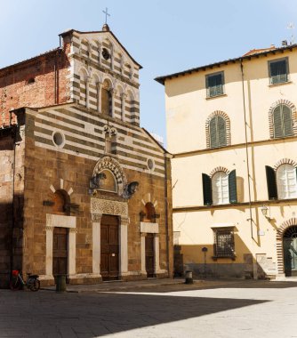 Lucca, İtalya 'daki Romanesk San Giusto Kilisesi cephesi, çizgili mermer bantlar, kör atari salonları, yuvarlak pencereler, yontulmuş portallar ve çan gable.
