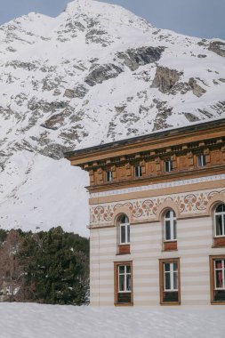 Maloja, İsviçre - Mart 2024: Karlı dağlarla çevrili zarif Maloja Palace Hotel 'in mimarisi 