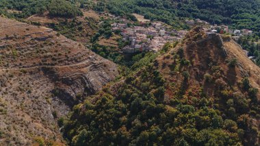 Sasso di Castalda, İtalya - Ağustos 2024: Bir hava manzarası, çevresindeki yeşil ve kahverengi yapraklarla kayalık bir arazide uzanan uzun ve askıya alınmış bir yaya köprüsünü yakalar, maceracı manzarayı ve mühendisliği vurgular..