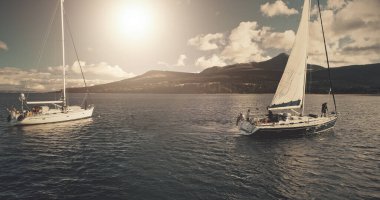 Sun over sailing regatta on luxury yachts aerial. Cinematic seascape of yachting summer sunny day. Panorama drone shot. Majestic sail boats race at ocean bay in Brodick harbour, Arran Island, Scotland clipart