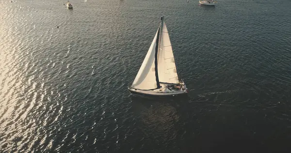 帆ボートと海面上の航空太陽の光 穏やかなウォーターフロントでヨットクルーズ オープンオーシャンベイでのヨットの夏休みの風景 船は風に乗って航行する シネマティックドローン撮影 — ストック写真