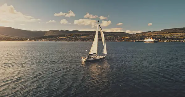 远洋海岸航空母舰 乘坐豪华游艇的夏季游轮 苏格兰海滨绿山的阿兰岛 在令人惊奇的海面上的水上交通工具拍摄无人驾驶电影 图库照片