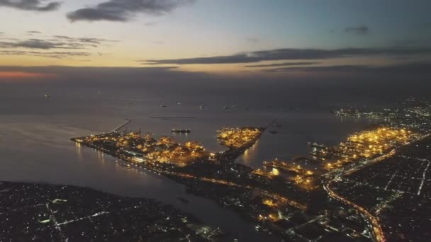 海の湾の空中でライトアップされた街並み 薄明かりの街でネオン マニラ フィリピンのナイトライフスタイルの道路や通りとメトロポリス都市 映画ソフトドローンショットの劇的な風景 ストック動画