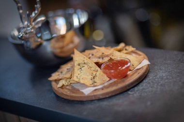 Meksika usulü nachos tortilla cipsi, kırmızı biberli makarna, yuvarlak ahşap bir tabakta, gümüş tabakta.