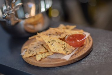 Meksika usulü nachos tortilla cipsi, kırmızı biberli makarna, yuvarlak ahşap bir tabakta, gümüş tabakta.