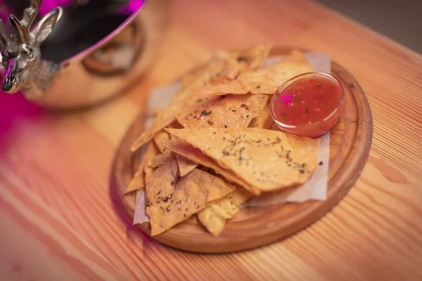 Meksika usulü nachos tortilla cipsi, kırmızı biberli, ahşap bir tabakta gümüş tabakta.