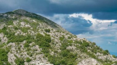 Zaman ayarlı Kümülüs bulutları kayalık bir tepenin üzerinde hareket eder