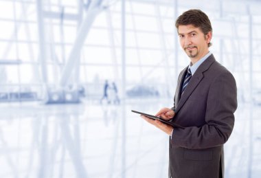 Ofiste elinde tablet olan genç bir işadamı var.