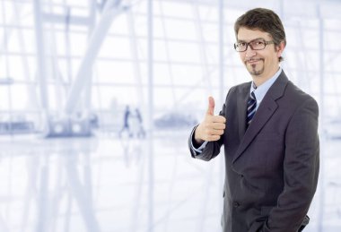 Genç iş adamı ofiste başparmağını kaldırıyor.