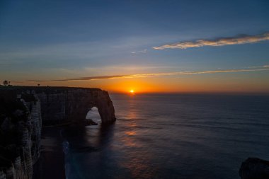 Etretat, Fransa sahillerinde dramatik bir gün batımı. Etretat, Alabaster kıyısındaki Etretat 'ın büyüleyici uçurumlarıyla ünlü büyüleyici bir kasabadır.