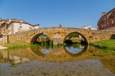 Navarre, Spain: Pilgrims walking over the medieval bridge part of the pilgrim route the Camino de Santiago the way of St James in the village of Villatuerta. Spain clipart