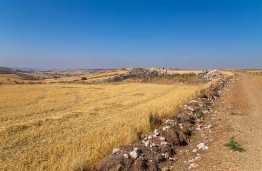 Rural road in the Spanish countryside among agricultural fields, after wheat harvest season. Navarra, Spain