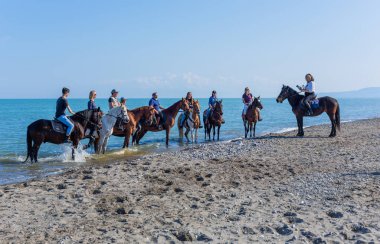 Policoro, İtalya: İtalya 'nın güneyindeki Basilicata, Policoro plajında at süren insanlar.