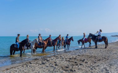 Policoro, İtalya: İtalya 'nın güneyindeki Basilicata, Policoro plajında at süren insanlar.