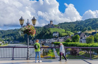 Cochem, Almanya. İnsanlar, Almanya 'nın Rhineland-Palatinate kentindeki Moselle' in Cochem kasabasında nehir boyunca yürüyorlar..