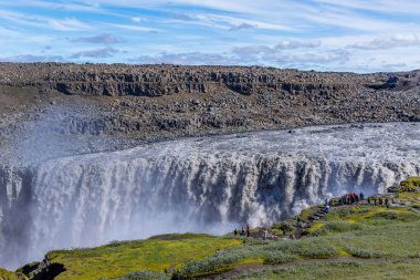 Vatnajokull, İzlanda: Kuzeydoğu İzlanda 'daki Dettifoss şelalesinin yamacındaki insanlar. Dettifoss, Vatnajokull Ulusal Parkı 'ndaki bir şelaledir. Avrupa' nın en güçlü şelalelerinden biridir.
