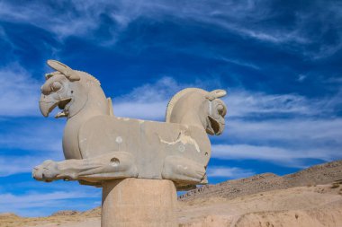 İran 'ın antik Persepolis kentinde iki başlı bir griffinin taş kolon heykeli. Unesco Dünya Mirası Bölgesi. Mavi gökyüzü arka planında