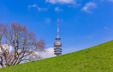 Münih, Almanya: Olympia Park 'taki Olympiaturm (Olympia Kulesi). Parkın ağaçlarından yukarı bakıyorum. Olimpiyat oyunları için yapılmış, Münih, Almanya