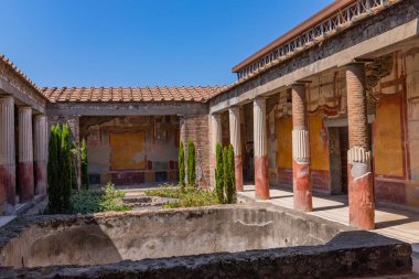 Pompei, İtalya: Dioscuri arkeolojik kalıntılarının evi. Avluda taş bir yapının yanında sütunları olan antik kalıntılar. MS 79 'da Vesuvius Dağı' nda meydana gelen volkanik patlamadan sonra kalmıştır..