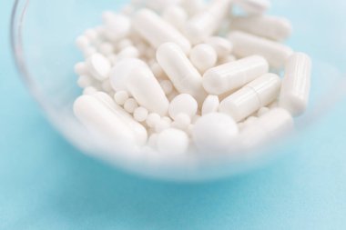 Farklı beyaz haplar ve mavi arka planda plastik bir kap. Tıbbi tema.