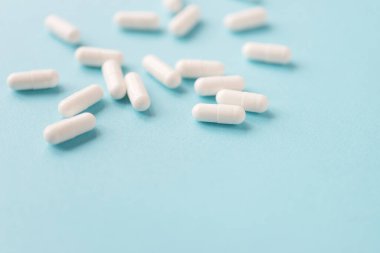 Mavi arka planda beyaz kapsül hapları ve kopyalama alanı. Tıp ve sağlık konsepti.