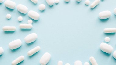 Mavi arka planda beyaz haplar ve fotokopi alanı. Tıp ve sağlık konsepti.