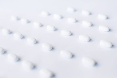 Scattered white pills on white background. Mock up for special offers as advertising, web background or other ideas. Medical, pharmacy and healthcare concept. Copy space.
