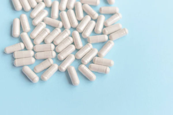 stock image Scattered white pills on a blue background. Model special offers as advertising, web background or other ideas. concept of medicine, pharmacy and health. copyright. Empty space for text or logo.