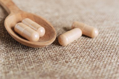 Tuvalin arka planında tahta kaşıkta sağlıklı bitkisel malzemeler. Haplar ve haplar..