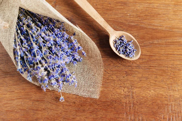 Ahşap bir arka planda ahşap bir kaşıkta lavanta çiçekleri ve lavanta tomurcukları. Aromaterapi.