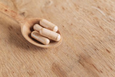 Ahşap bir arka planda tahta kaşıkta sağlıklı bitkisel takviyeler. Haplar ve haplar..