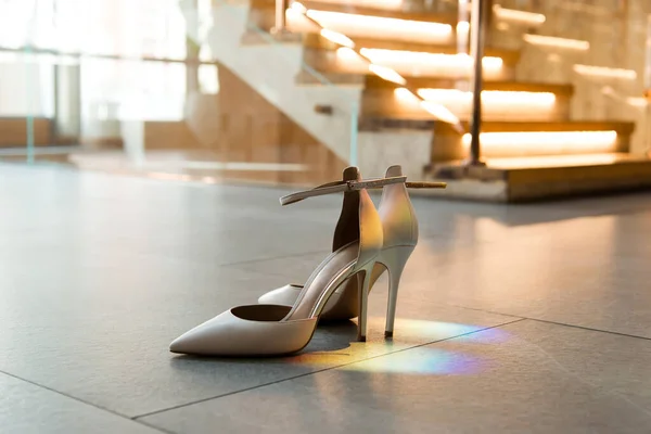 Women\'s elegant classic white shoes on the floor. Rainbow flare.