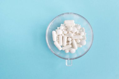 Mavi masaya saçılmış beyaz haplar. Reklam, web geçmişi ya da diğer fikirler için özel teklifler alın. Tıbbi, eczane ve sağlık hizmetleri konsepti. Uzayı kopyala Metin veya logo için boş yer