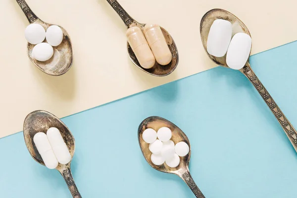 Pastel Arka Planda Çay Kaşıklarıyla Farklı Tabletler Kapsüller Haplar Haplar — Stok fotoğraf