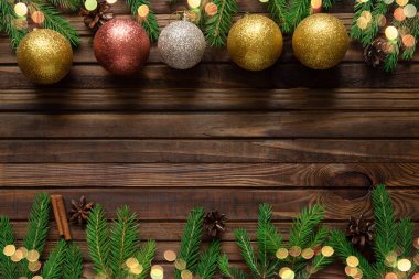 Noel ağacı dallarından yapılmış Noel çerçevesi oyuncakları ve tarçın çubukları ile koyu ahşap arka planda bokeh ışıkları, kopyalama alanı