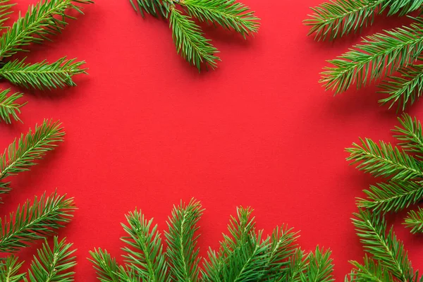 クリスマスツリーの枝で作られたクリスマスフレームは プレーンペーパーレッドの背景にボケライト コピースペース — ストック写真