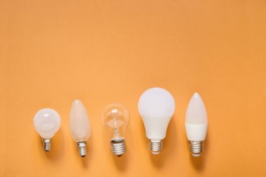 Turuncu arka planda beş farklı ampul.