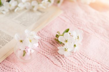 Narin pembe örülmüş arka planda küçük cam bir vazoda kiraz çiçekleri.