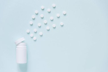 Mavi masaya saçılmış beyaz haplar. Reklam, web geçmişi ya da diğer fikirler için özel teklifler alın. Tıbbi, eczane ve sağlık hizmetleri konsepti. Uzayı kopyala Metin veya logo için boş yer