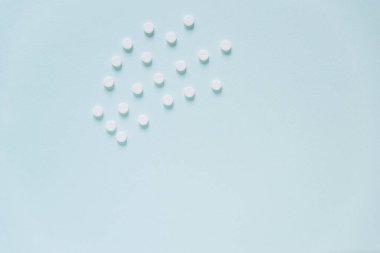 Mavi masaya saçılmış beyaz haplar. Reklam, web geçmişi ya da diğer fikirler için özel teklifler alın. Tıbbi, eczane ve sağlık hizmetleri konsepti. Uzayı kopyala Metin veya logo için boş yer