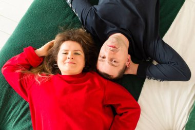 Sıcak bir ev ortamında bir erkek ve bir kadın yatakta sarılıyorlar. Bir adam ve bir kız, kazak ve kot giyen güzel bir çift sevgili..