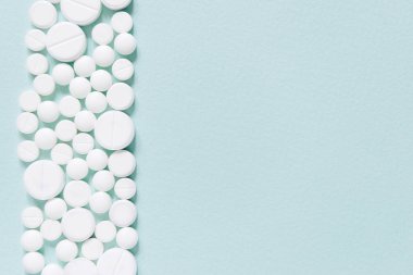 Mavi masaya saçılmış beyaz haplar. Reklam, web geçmişi ya da diğer fikirler için özel teklifler alın. Tıbbi, eczane ve sağlık hizmetleri konsepti. Uzayı kopyala Metin veya logo için boş yer