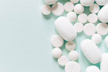 Mavi masaya saçılmış beyaz haplar. Reklam, web geçmişi ya da diğer fikirler için özel teklifler alın. Tıbbi, eczane ve sağlık hizmetleri konsepti. Uzayı kopyala Metin veya logo için boş yer