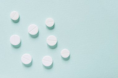 Mavi masaya saçılmış beyaz haplar. Reklam, web geçmişi ya da diğer fikirler için özel teklifler alın. Tıbbi, eczane ve sağlık hizmetleri konsepti. Uzayı kopyala Metin veya logo için boş yer