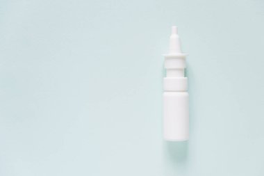 White plastic bottle of medical nasal spray on a blue background. Pharmaceutical packaging layout. Allergy runny nose remedy, rhinitis therapy.