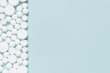 Mavi masaya saçılmış beyaz haplar. Reklam, web geçmişi ya da diğer fikirler için özel teklifler alın. Tıbbi, eczane ve sağlık hizmetleri konsepti. Uzayı kopyala Metin veya logo için boş yer