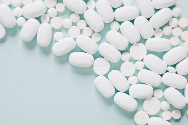 Mavi masaya saçılmış beyaz haplar. Reklam, web geçmişi ya da diğer fikirler için özel teklifler alın. Tıbbi, eczane ve sağlık hizmetleri konsepti. Uzayı kopyala Metin veya logo için boş yer